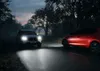 Two cars driving on a road at dusk with headlights on. Produktbild-Vorschau