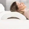 A woman is lying on her side on a bed, resting her head on a white, curved pillow. Anteprima dell’immagine prodotto