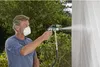 A man is using a paint sprayer outdoors, painting a white wall. Náhľad obrázku produktu