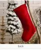 A red Christmas stocking hangs from a branch in front of a snowy Christmas tree and a brick wall. Náhľad obrázku produktu