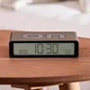 A digital alarm clock is placed on a wooden table. Podgląd zdjęcia produktu