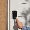 A hand is pressing a doorbell button mounted on a white wall next to a wooden door. Náhľad obrázku produktu