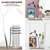 A collage of images showing a decorative picture frame with a glass vase and a metal tree design, displayed on a shelf with makeup brushes and a flower. Produktbild-Vorschau