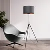 A modern living room scene with a gray armchair and a black tripod floor lamp. Produktbild-Vorschau