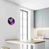 A modern kitchen with a wooden counter and light blue cabinets, featuring a wall clock with a butterfly design. Produktbild-Vorschau