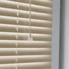 A close-up view of beige horizontal blinds with a pull cord. Produktbild-Vorschau