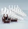 A collection of plastic pipe clips in white and brown, arranged in rows on a light gray background. Náhľad obrázku produktu