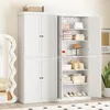 A white storage cabinet with multiple doors and shelves, filled with various items like bags, folded clothes, hats, and shoes. It is placed in a room with a mirror and a plant. Voir les images du produit