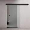 A frosted glass sliding door with a black handle and track, installed in a modern interior. Part of a bedroom is visible through the partially open door. Produktbild-Vorschau