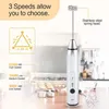 A silver electric milk frother with a stainless steel whisk attachment is shown on a countertop. Text overlays highlight its features, including three speed settings and the stainless steel spring head. Background shows kitchen appliances. Produktbild-Vorschau