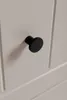 A close-up shot of a black cabinet knob on a beige cabinet door. Náhľad obrázku produktu