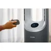 A hand holding a remote control and aiming it towards a modern fan. Podgląd zdjęcia produktu