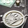 A close-up of a place setting with silverware on a plate, with decorative elements in the background. Náhled obrázku produktu