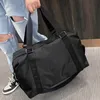 A person is holding a black duffel bag, wearing ripped jeans and sneakers. Voir les images du produit