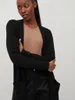 A woman wearing a black cardigan over a tan top. Produktbild-Vorschau