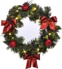 A Christmas wreath decorated with red bows, red apples, and LED lights. Produktbild-Vorschau