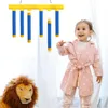 A young child is playing with a hanging toy, with a stuffed lion in the foreground. Náhled obrázku produktu