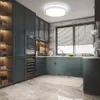 A modern kitchen with dark blue cabinets, a large window with blinds, and a ceiling light. Podgląd zdjęcia produktu