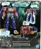 The image shows the back of a Transformers Optimus Prime toy box, featuring the robot in both robot and vehicle modes, along with various text and graphics highlighting its features. Podgląd zdjęcia produktu