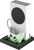 A white Xbox Series S console is shown vertically on a black docking station with a white controller in front of it. The docking station has green LED lighting. Náhľad obrázku produktu