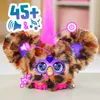A close-up marketing shot of a Furby Furblet toy with various icons and text overlays indicating features. Produktbild-Vorschau