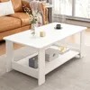A white coffee table with a shelf is placed in a living room setting, next to a brown leather sofa. Produktbild-Vorschau