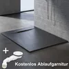 A black shower tray with a slate-like texture is shown on a tiled floor, with a white drain assembly in the foreground. Text indicates a free drain set. Produktbild-Vorschau
