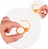 A hand holds an orange ring with a small bear charm and a yellow string. Produktbild-Vorschau