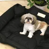 A Shih Tzu dog is sitting on a black dog bed. Anteprima dell’immagine prodotto