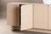 A close-up view of a light wood sideboard with curved doors. One door is slightly ajar, revealing shelving inside. Produktbild-Vorschau