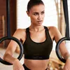 A woman is holding onto gymnastic rings in a gym. Produktbild-Vorschau