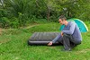 A man is setting up an air mattress outdoors next to a tent. Náhled obrázku produktu