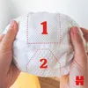 Hands holding a diaper with numbered sections. Podgląd zdjęcia produktu
