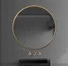 A modern round mirror with a gold frame is mounted on a gray wall above a black rectangular sink with rose gold faucets. Podgląd zdjęcia produktu