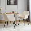 Two cream-colored accent chairs with black metal legs are positioned around a wooden dining table. A bowl of fruit sits on the table. Produktbild-Vorschau