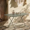 A folding bistro table set up outdoors on a stone patio, with a pitcher and glasses on the table. Anteprima dell’immagine prodotto