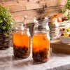 Several glass jars filled with a liquid and fruit, set against a wooden background. Podgląd zdjęcia produktu