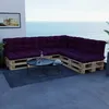 A sectional sofa made of wooden pallets with purple cushions is placed on a balcony overlooking the ocean. Voir les images du produit