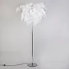 A white floor lamp with a metallic stand against a plain background. Produktbild-Vorschau