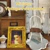 A collection of miniature vintage-themed decorative items, including picture frames, a doll, and a chair, arranged on a surface. Produktbild-Vorschau