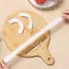 A hand is holding a roll of plastic food covers over a wooden cutting board with two plastic food covers already laid out. Produktbild-Vorschau