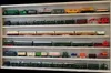 A white display shelf filled with various model trains and train cars. Produktbild-Vorschau