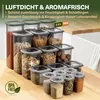 A collection of clear plastic food storage containers with gray lids, filled with various dry goods like grains, pasta, candies, and spices, arranged on a wooden surface with a white countertop and sink in the background. Anteprima dell’immagine prodotto