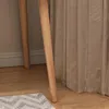 Close-up of wooden table legs next to a beige curtain and a rug. Anteprima dell’immagine prodotto