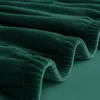 A close-up view of a folded green fabric, likely a sofa cover, showing its texture and stitching. Podgląd zdjęcia produktu
