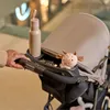 A person's hand is holding the handle of a stroller. A water bottle and a stuffed animal are in the stroller's organizer. Voir les images du produit