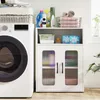 A white storage cabinet with two doors and shelves, placed next to a washing machine in a laundry room setting. Anteprima dell’immagine prodotto