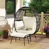 A rattan egg chair with cushions and a matching ottoman on a wooden deck, with plants and a railing in the background. Anteprima dell’immagine prodotto