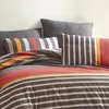 A close-up view of a striped duvet cover and pillows on a bed. Produktbild-Vorschau