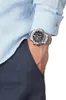 A close-up shot of a man's wrist wearing a silver watch, with his hand in his pocket. Náhled obrázku produktu
